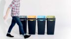 4 recycling bins of different colours, person walking past