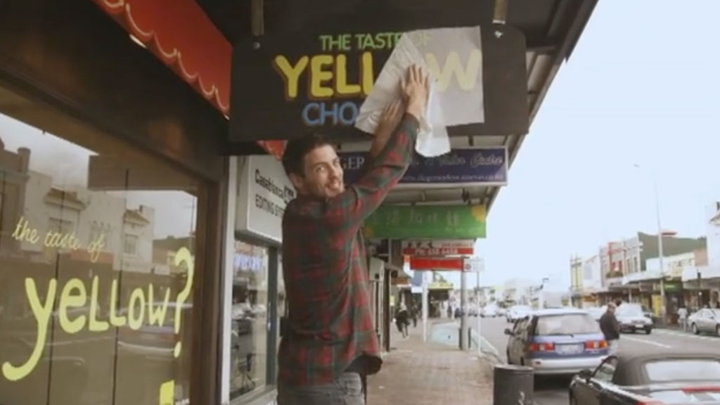person installing a sign that says "yellow chocolate"